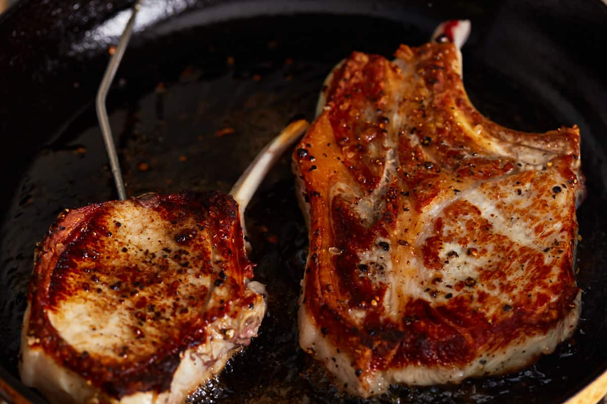 seared bone in pork chops in a cast iron pan.