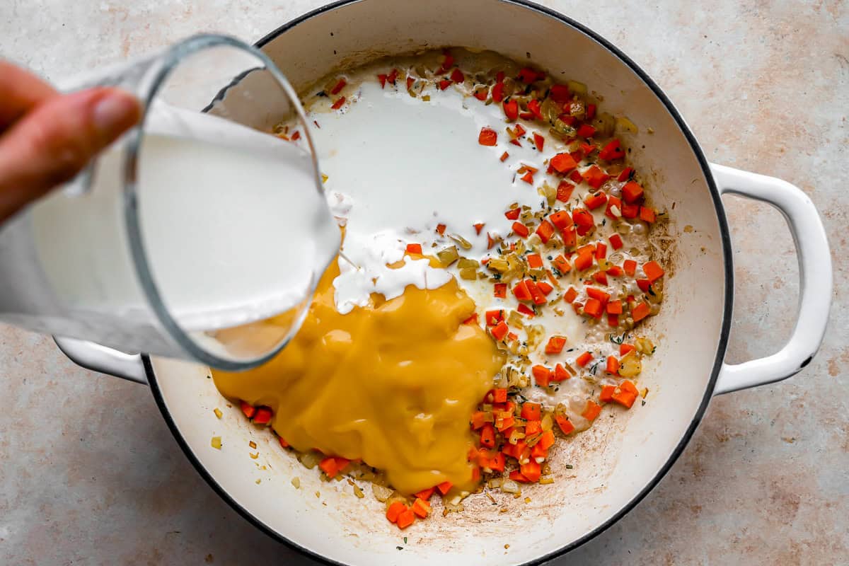 adding heavy cream and cream of chicken soup to sauteed veggies in a pot.