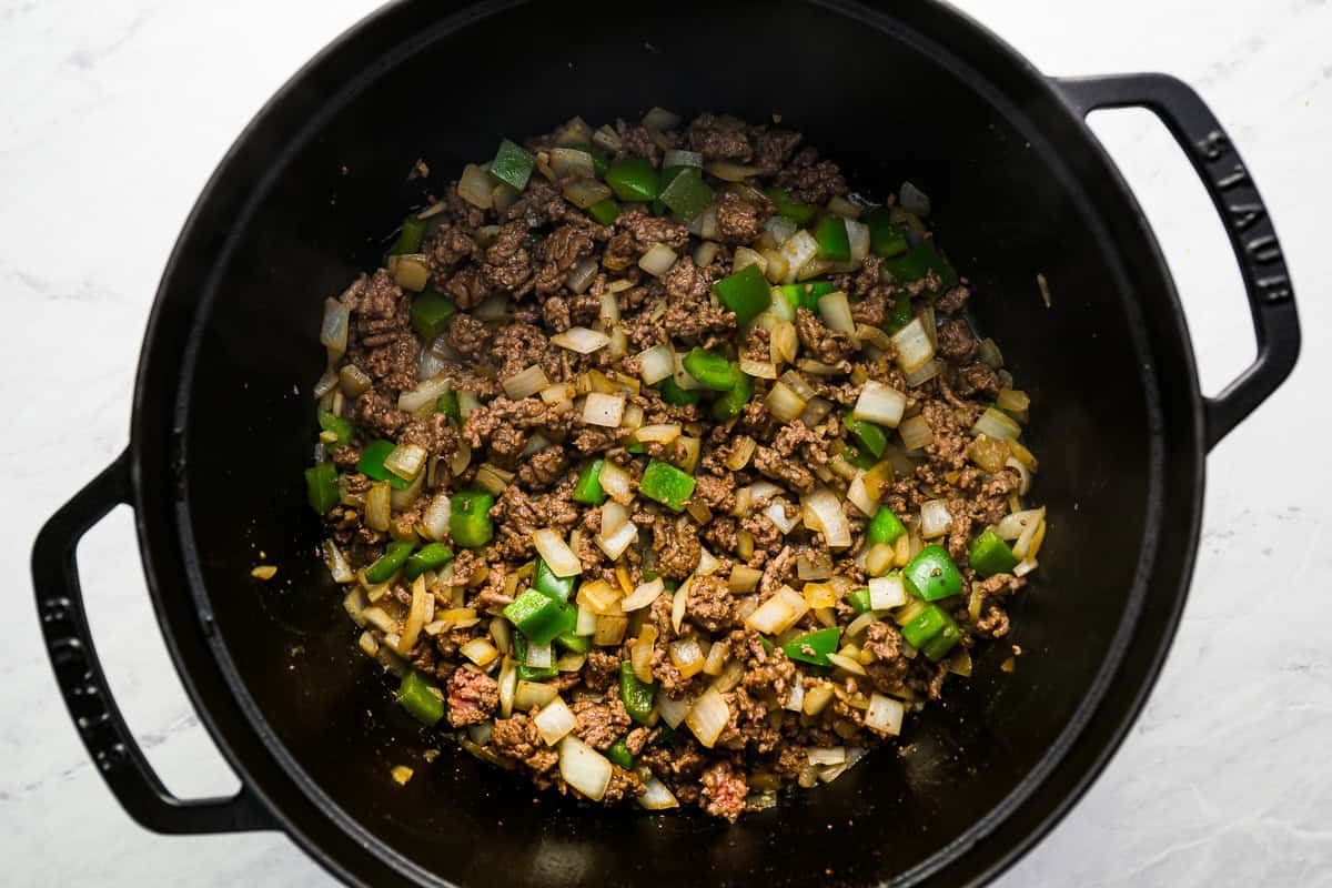 ground beef and veggies cooking in a dutch oven.