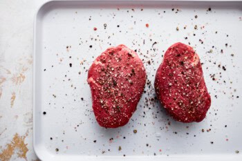 2 seasoned raw filets on a baking sheet.