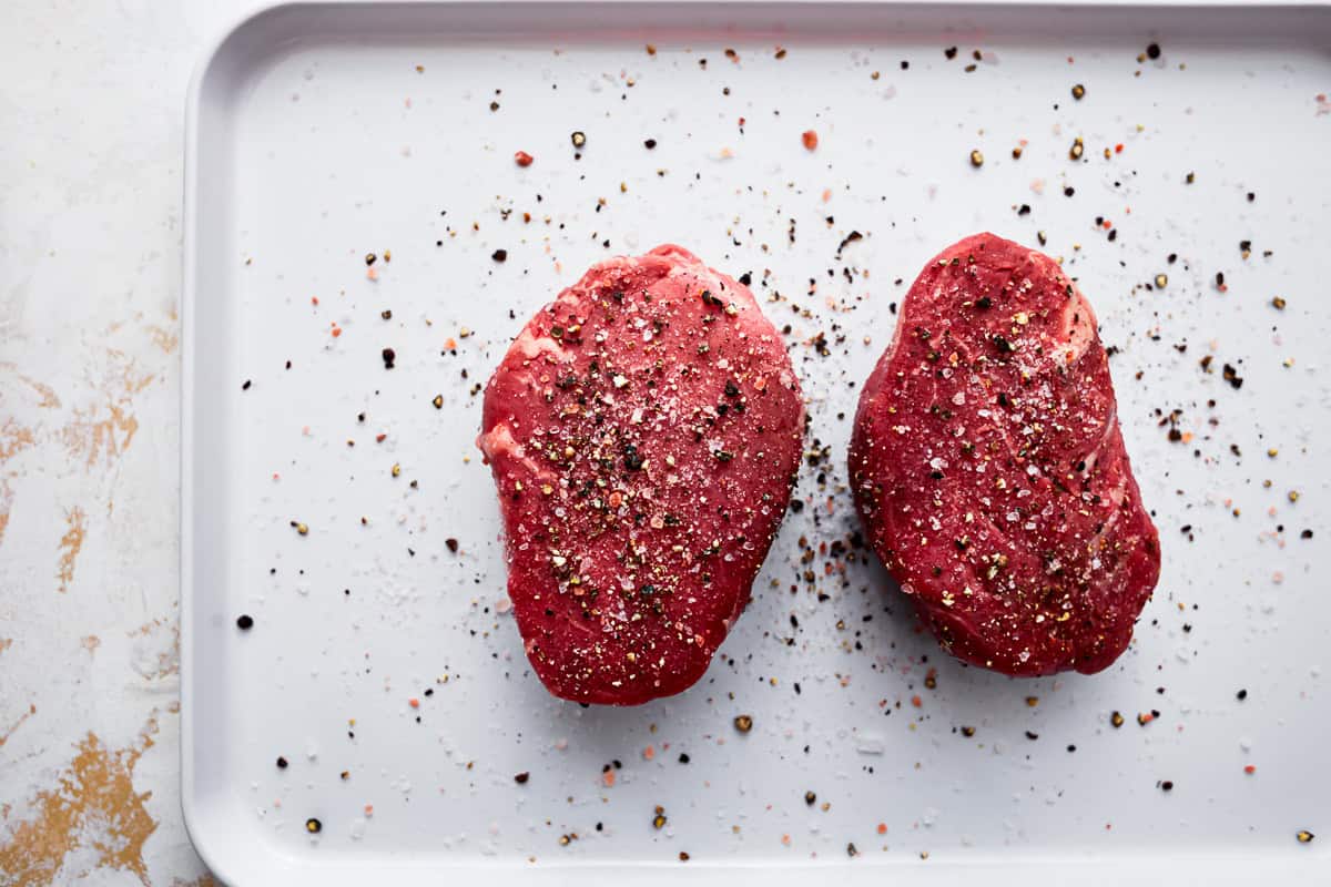 2 seasoned raw filets on a baking sheet.