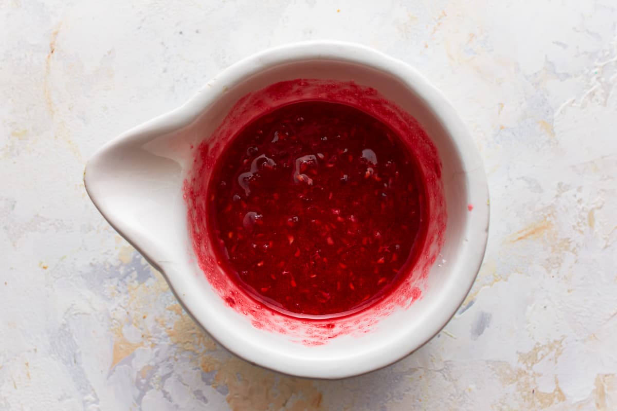 Muddled raspberry mixture in a ceramic container.