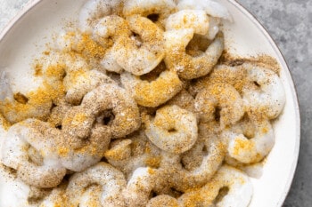 A plate of raw shrimp coated in a mix of spices.