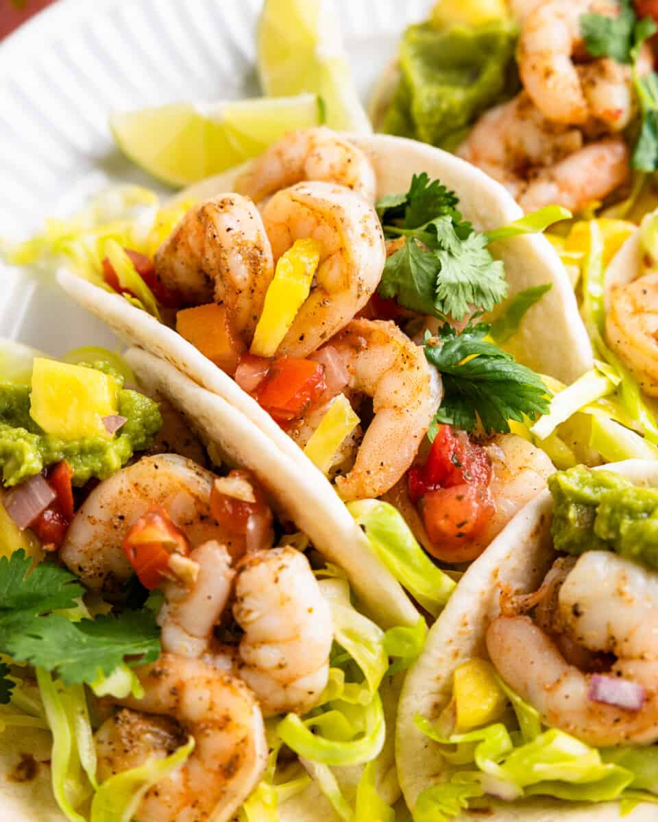 A plate of shrimp tacos with pineapple and cabbage slaw.