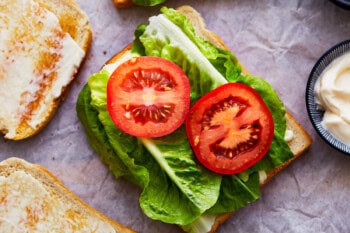 toasted bread topped with lettuce leaves and tomato slices.