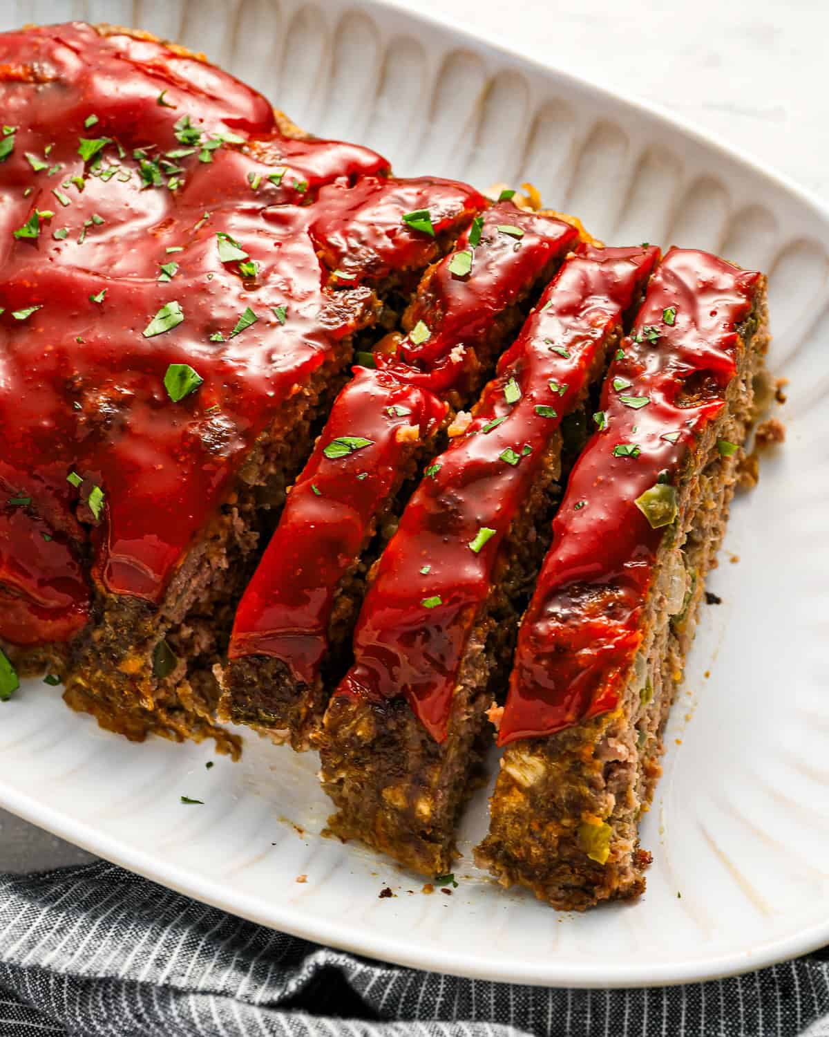 partially sliced cracker barrel meatloaf on a white serving platter.