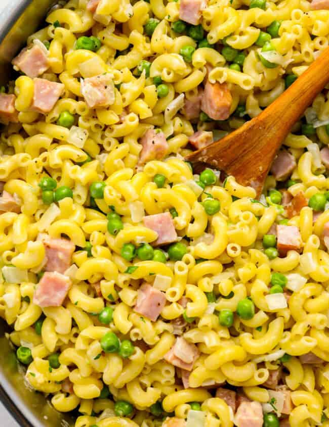 ham and pea pasta in a pot with a wooden spoon.