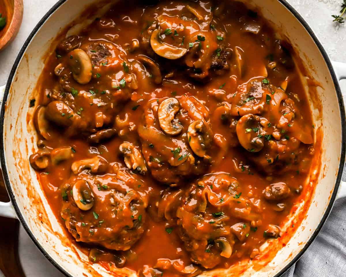 overhead view of hamburger steaks and gravy in a pan.