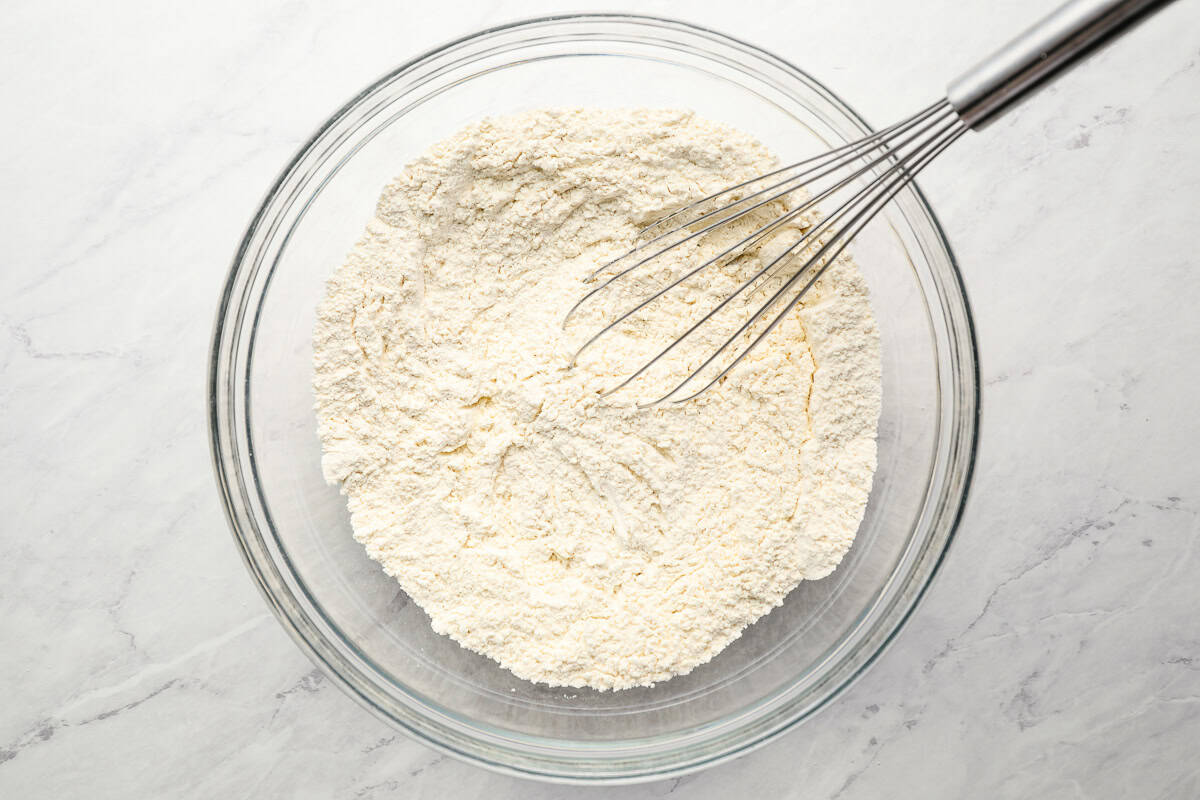 flour in a glass bowl with a whisk.