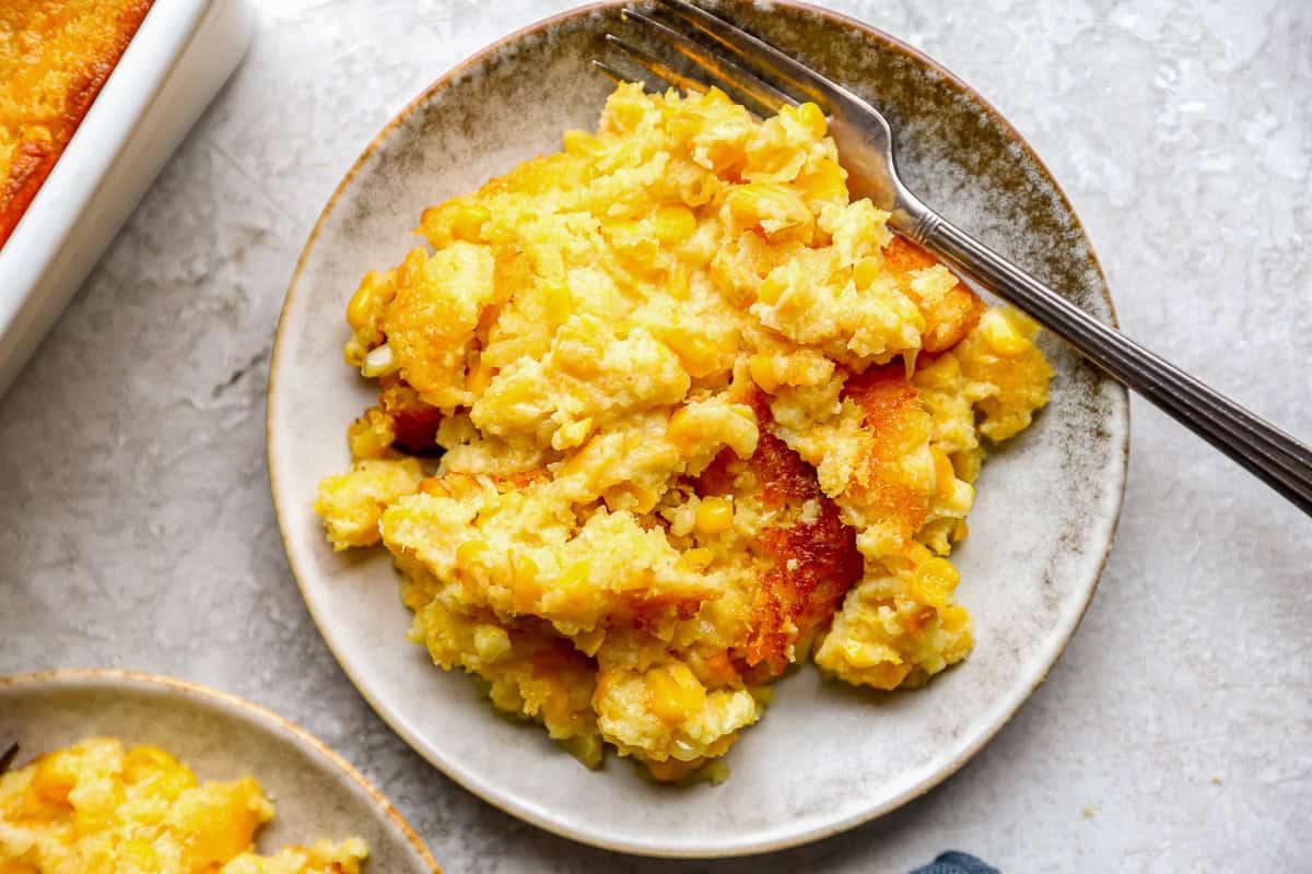 A serving of Jiffy corn casserole on a white plate with a fork.