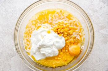 corn, creamed corn, egg, and sour cream in a glass bowl.