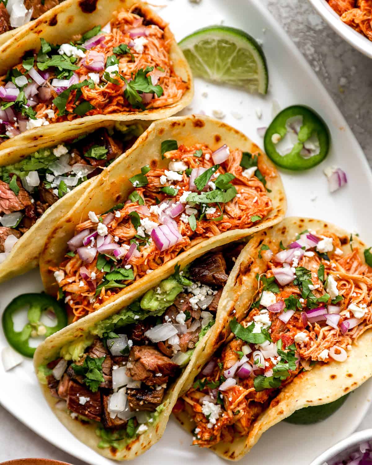 overhead view of street tacos on a white platter.