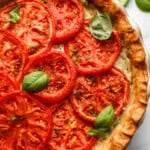 partial overhead view of a tomato pie topped with basil.