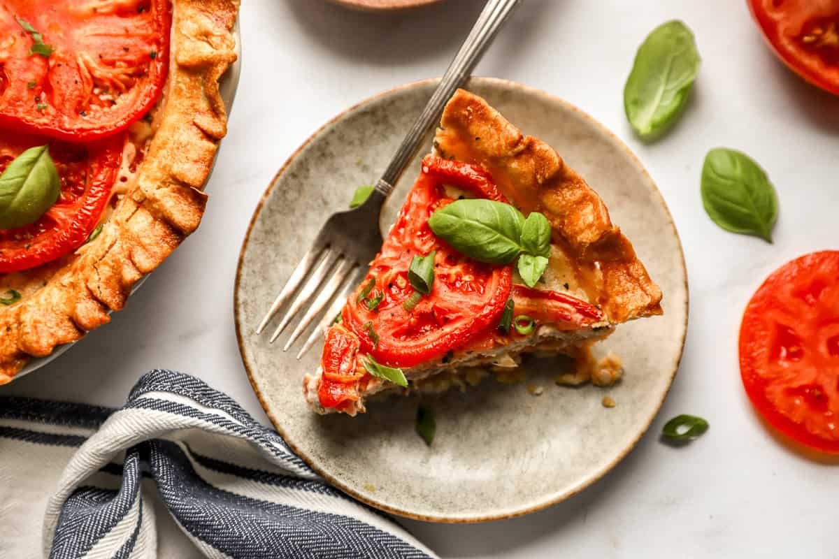 overhead view of a slice of tomato pie on a gray plate with a fork.