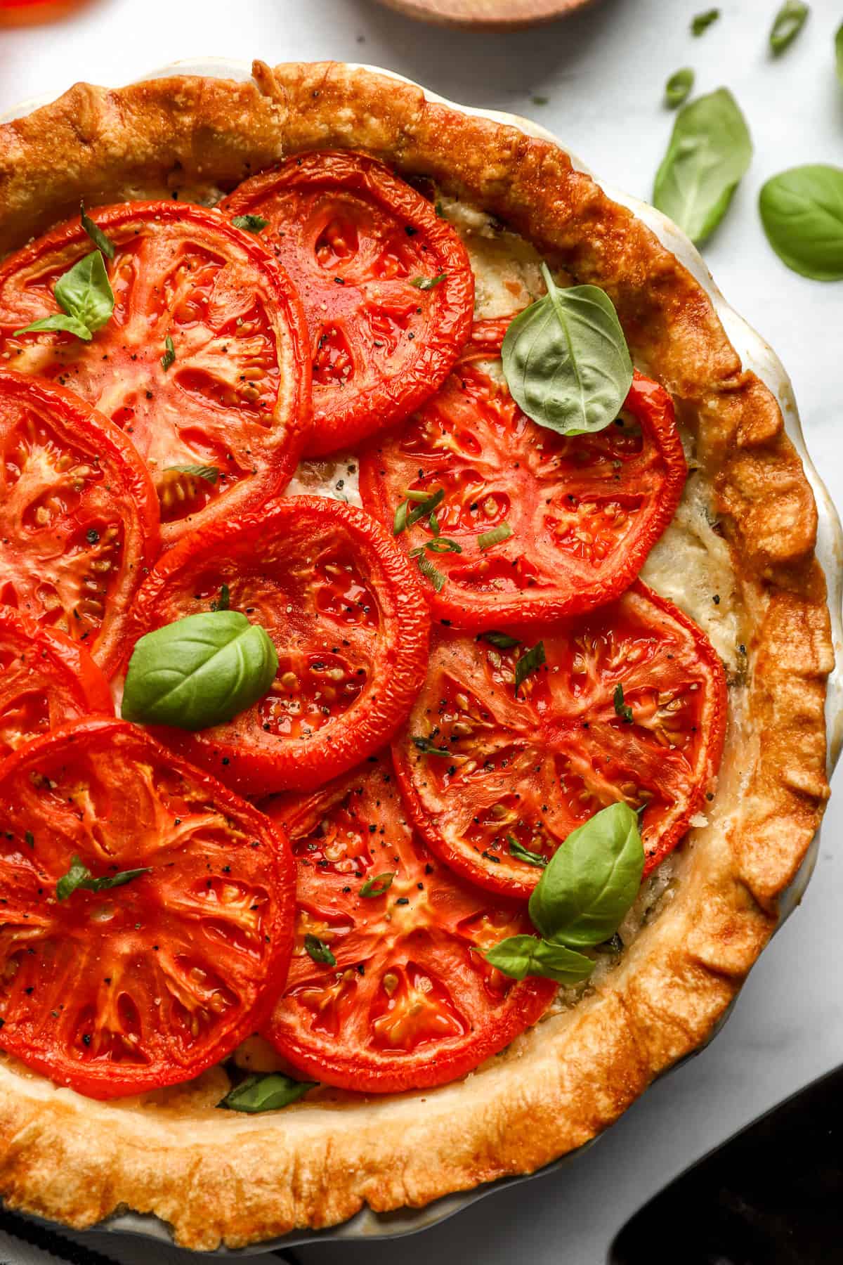 partial overhead view of a tomato pie topped with basil.