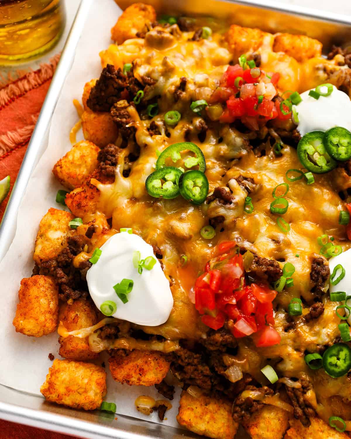 close up overhead view of loaded tater tots (totchos) on a baking sheet.