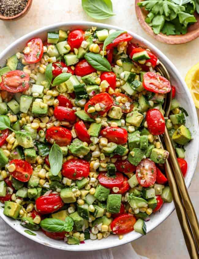 close up overhead view of avocado salad in a white bowl with a serving spoon.