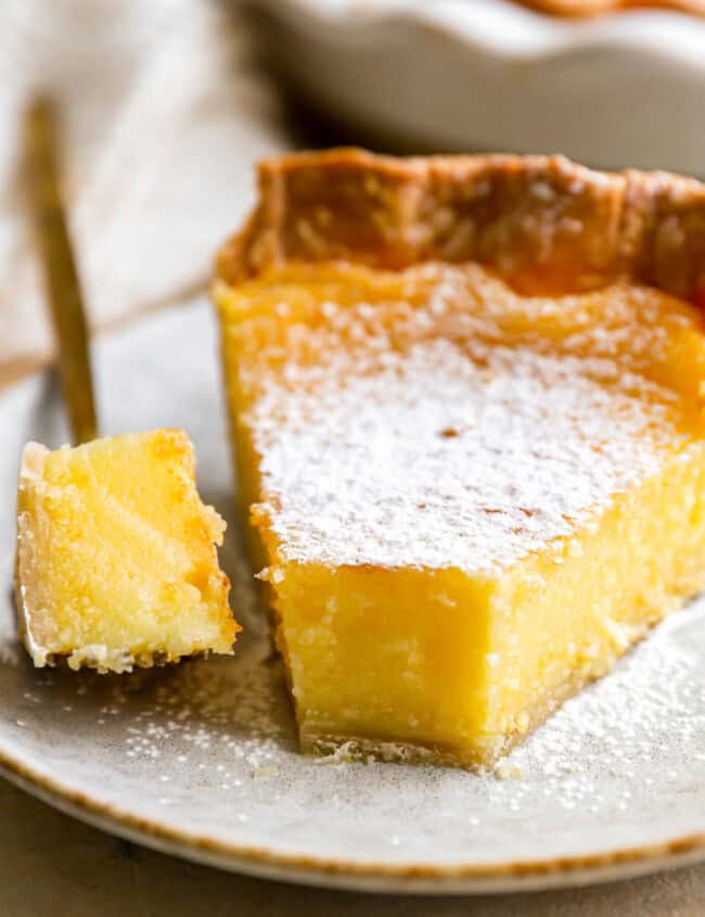 a forkful of chess pie next to a slice on a speckled plate.