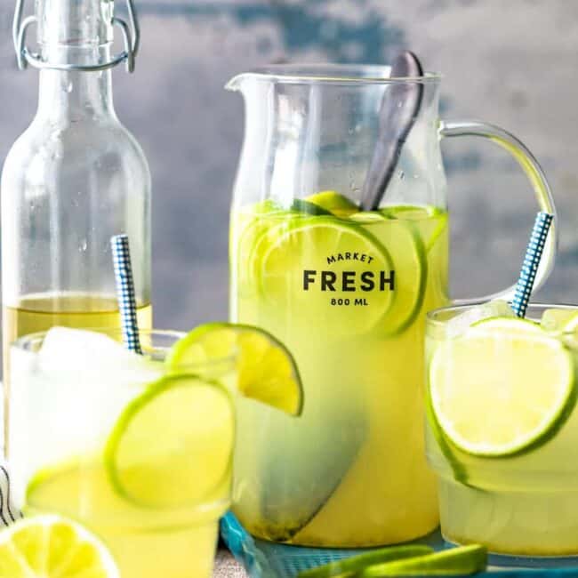 fresh lemonade and limeade in pitchers on a wooden table.