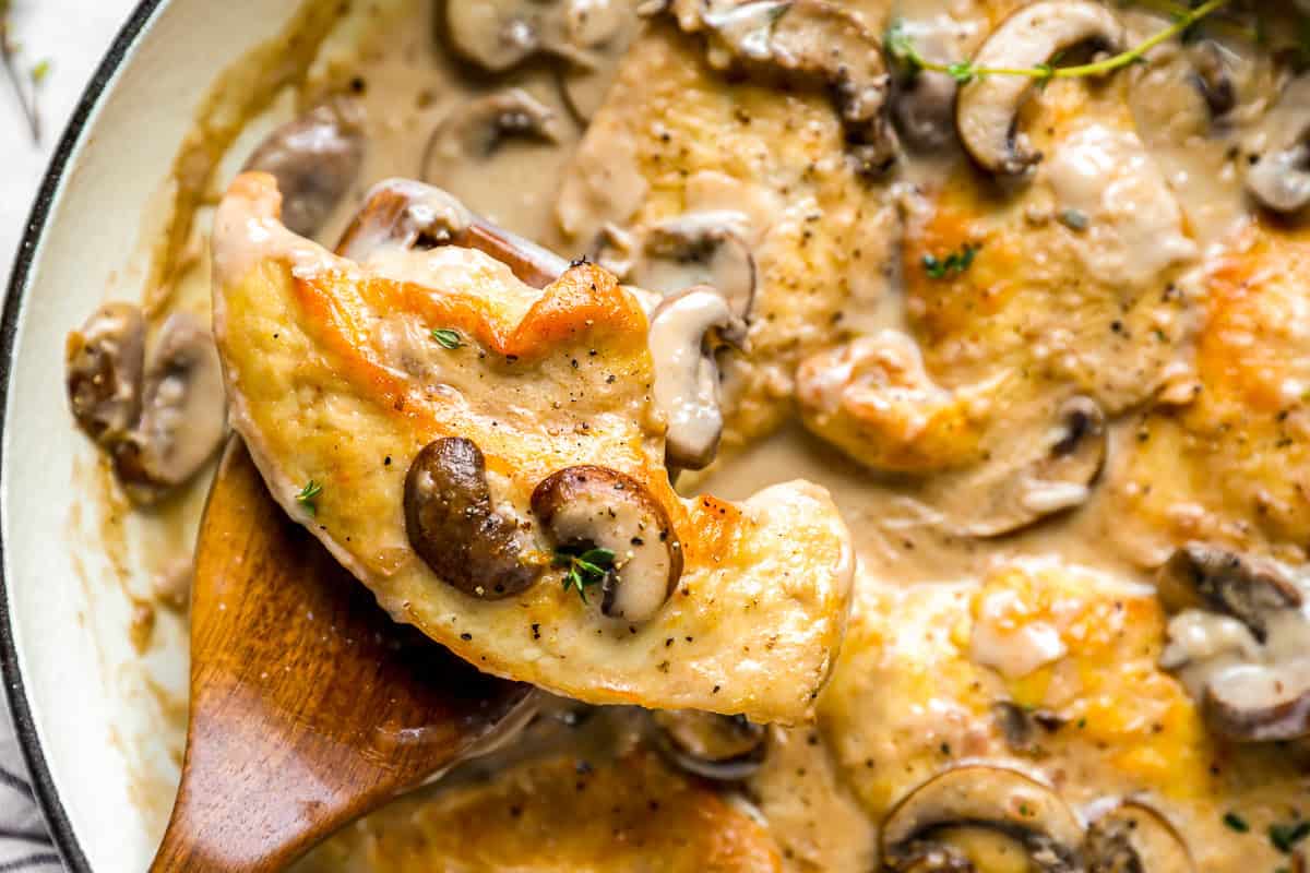 lifting a piece of mushroom chicken from a dutch oven.