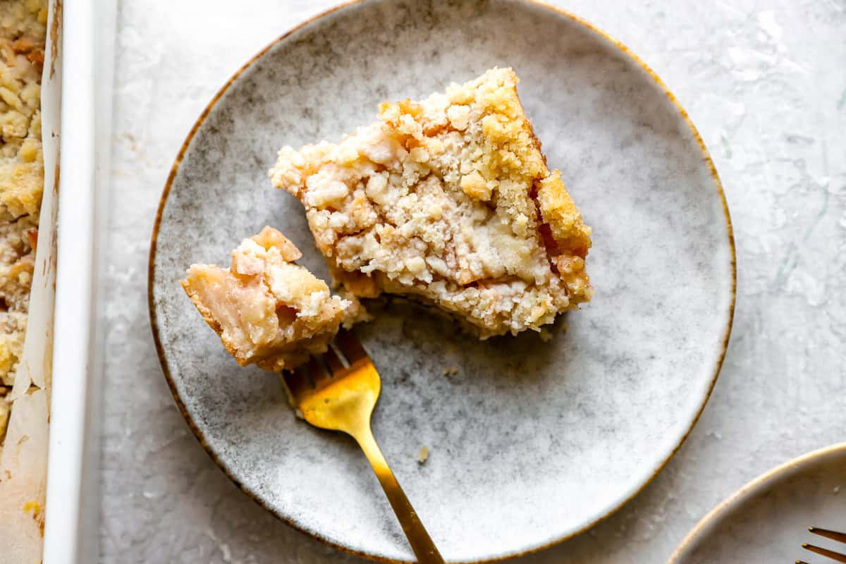 overhead view of a partially eaten apple pie bar on a white plate with a fork.