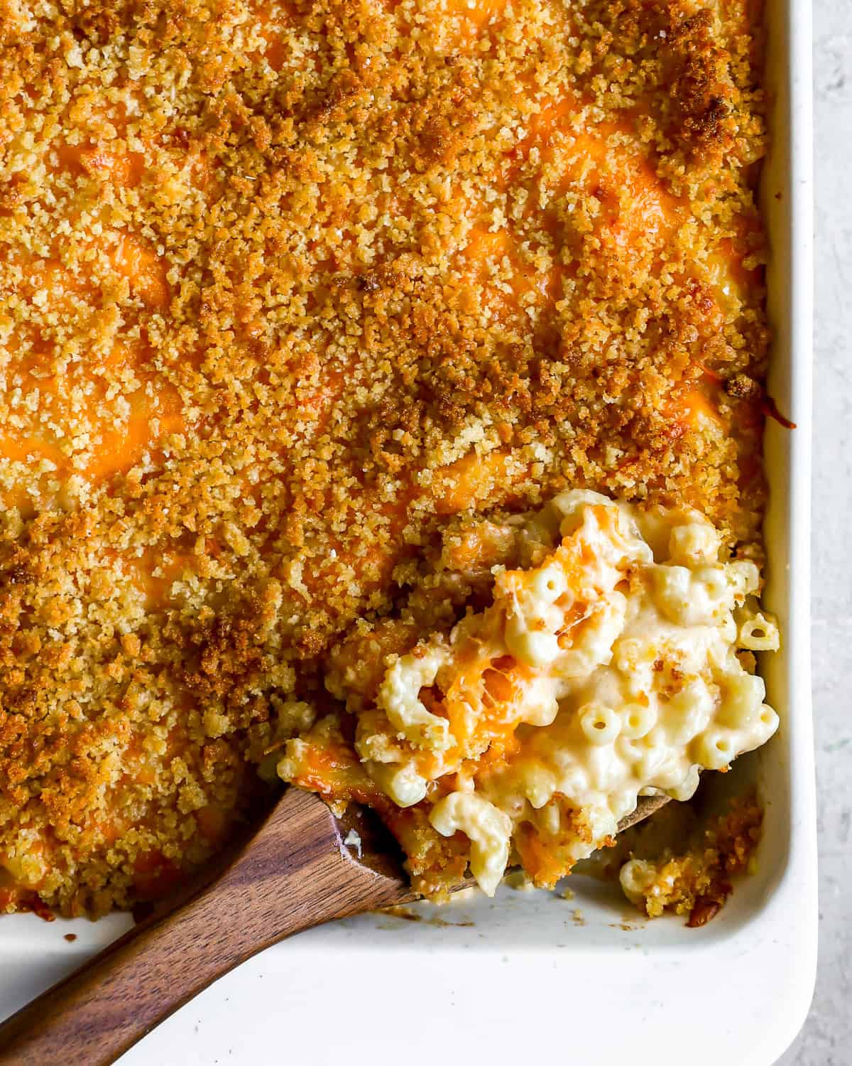 overhead view of a spoonful of baked mac and cheese resting in a casserole dish.