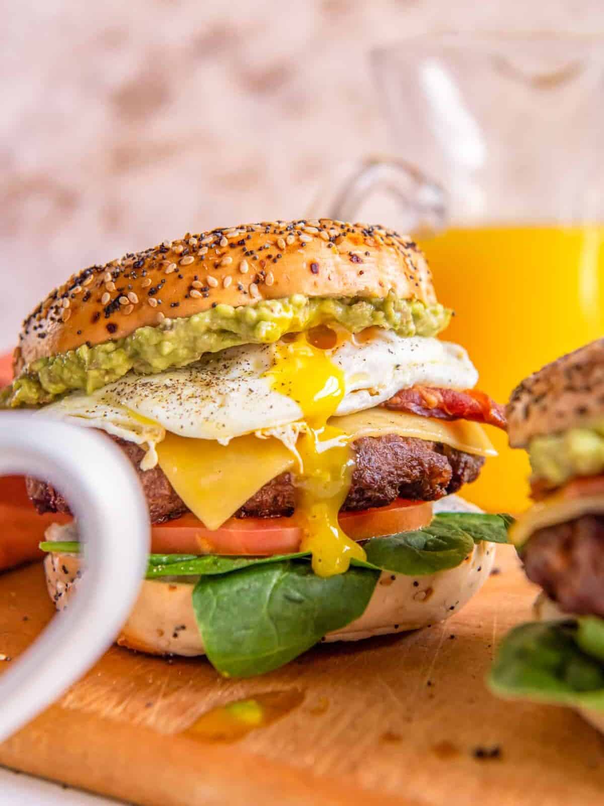 close up of a breakfast burger on a wooden cutting board.