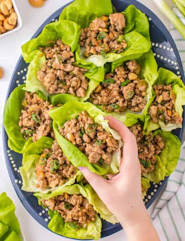 lifting up chicken lettuce wrap from platter