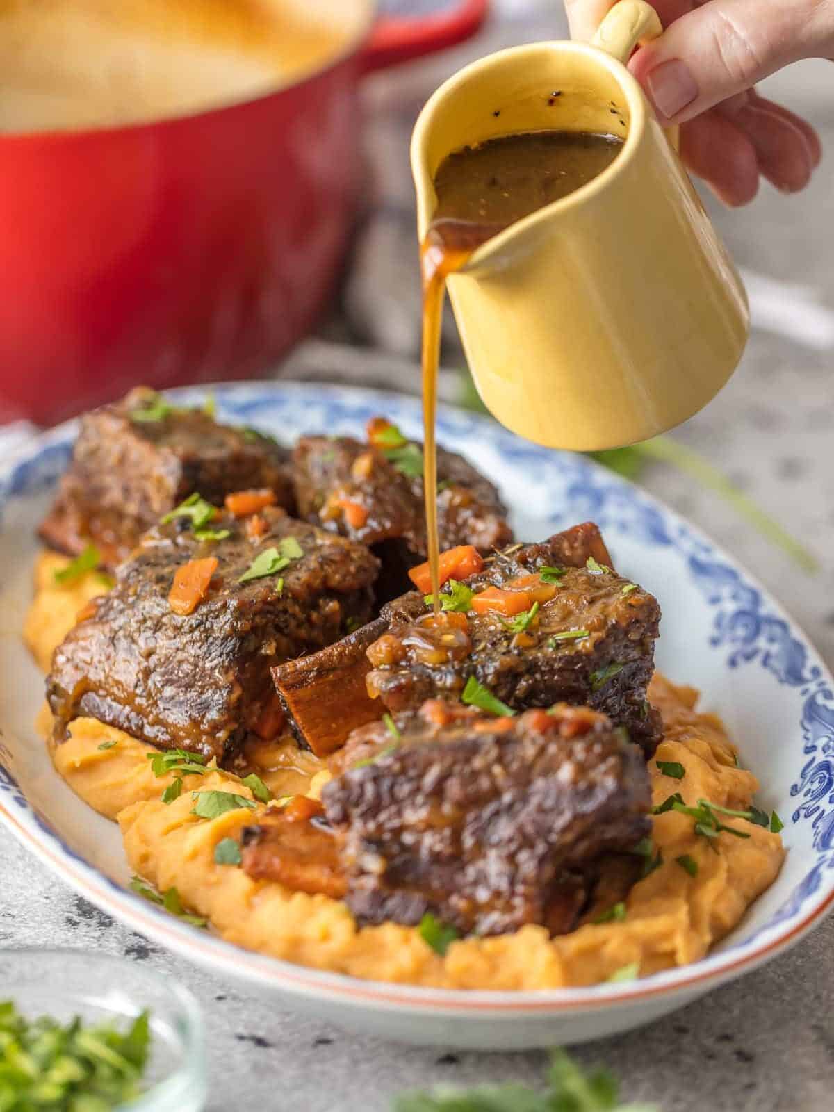 Pouring honey bourbon glaze over plate of short ribs