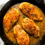 overhead view of 4 honey mustard chicken breasts in a cast iron skillet.