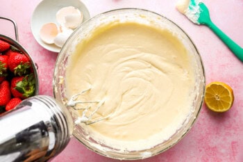 beaten cheesecake filling in a glass bowl with a hand mixer.