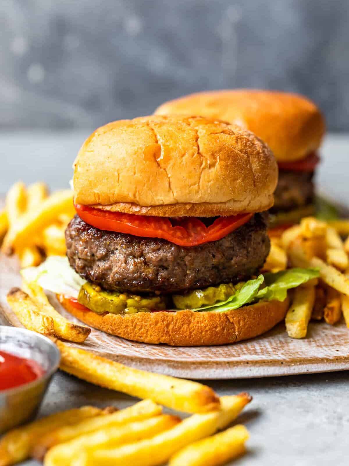 hamburger on a bun topped with pickles, lettuce, and tomato