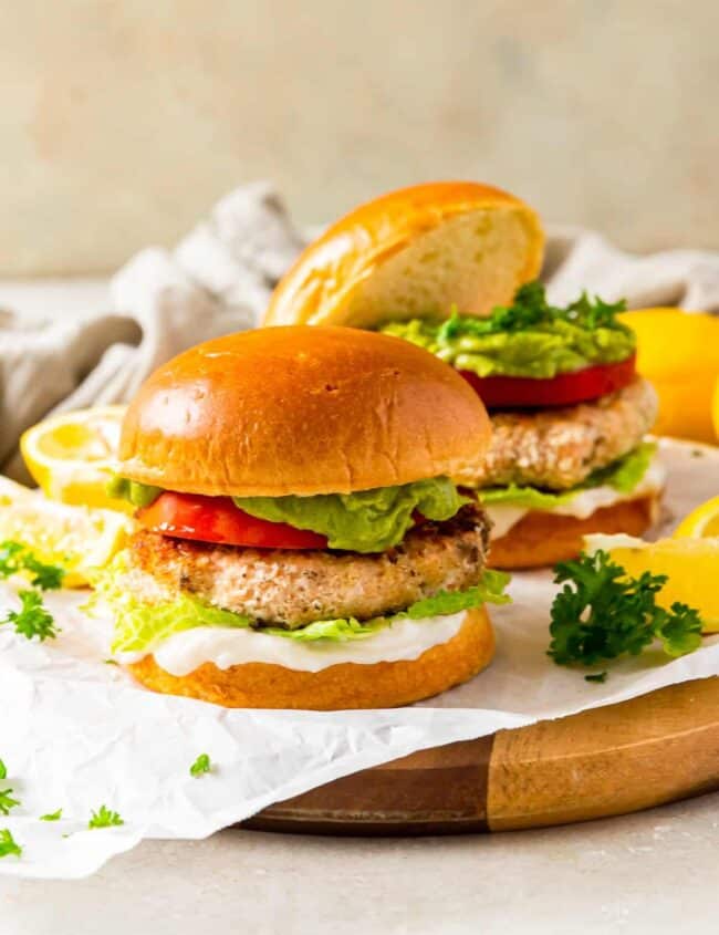 salmon burger on a bun topped with tomato, lettuce, guacamole