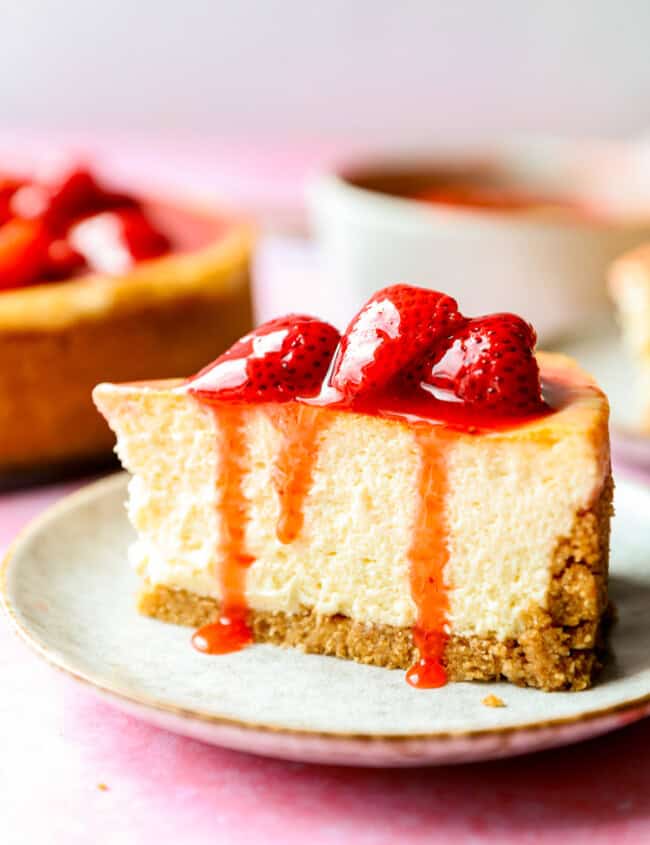 side view of a slice of cheesecake with strawberry sauce on top.