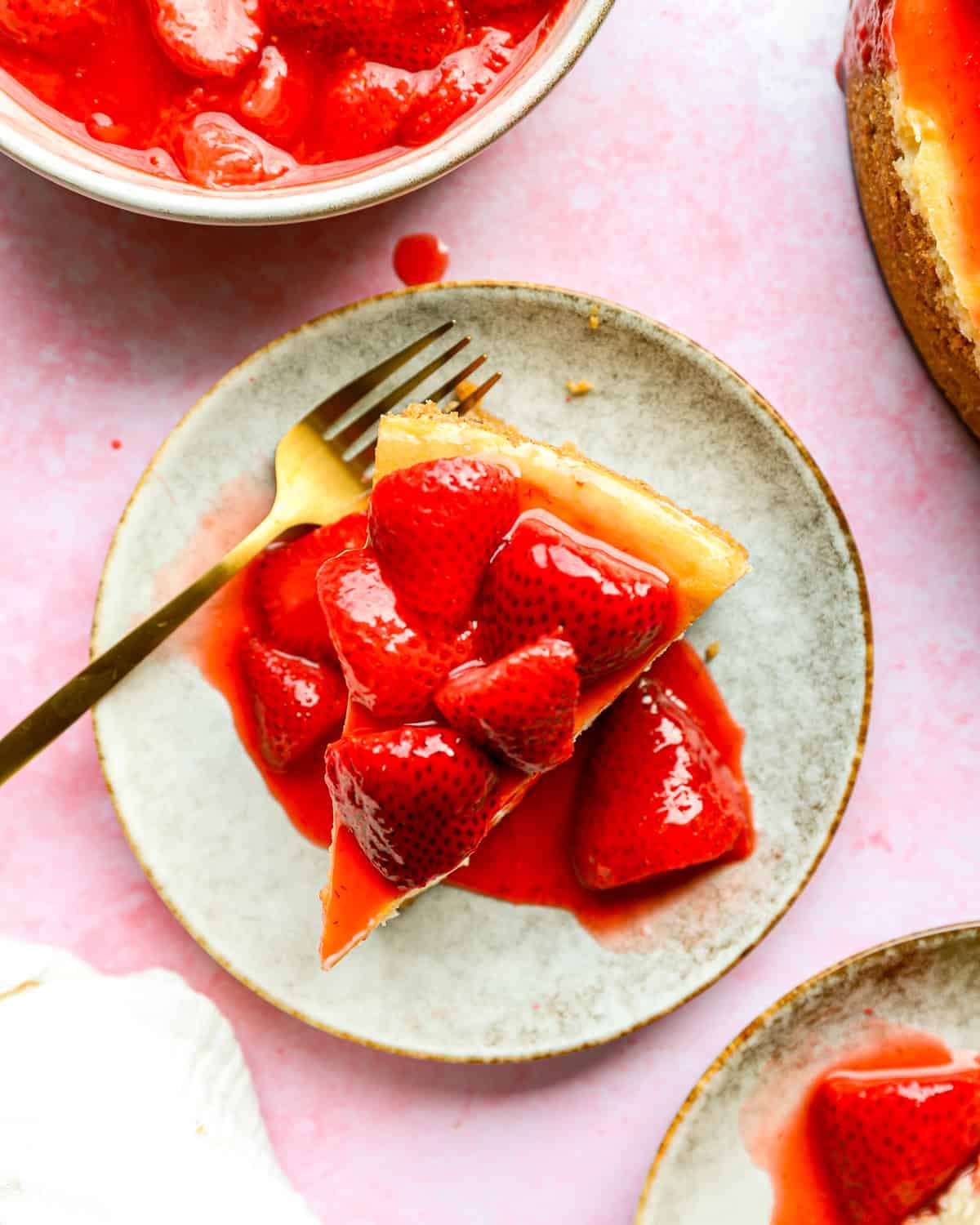 overhead view of a slice of strawberry cheesecake on a plate with a fork.