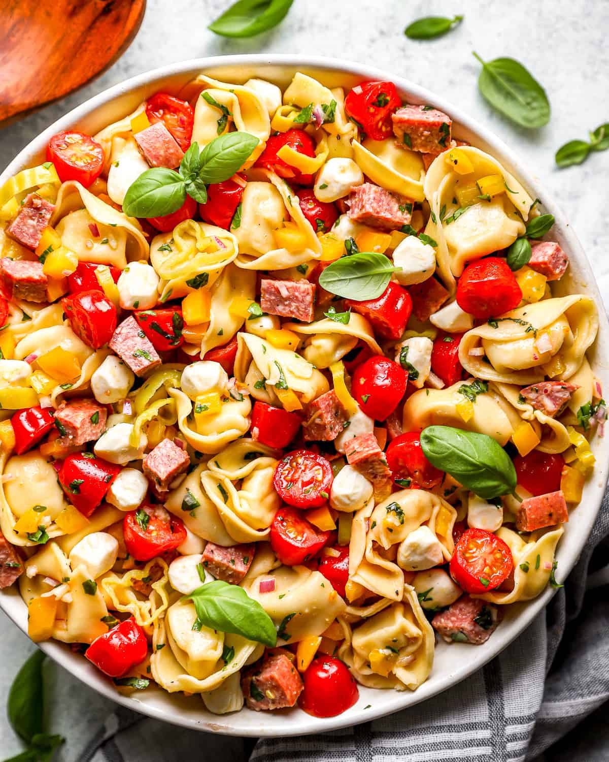 overhead view of tortellini pasta salad in a white serving bowl.