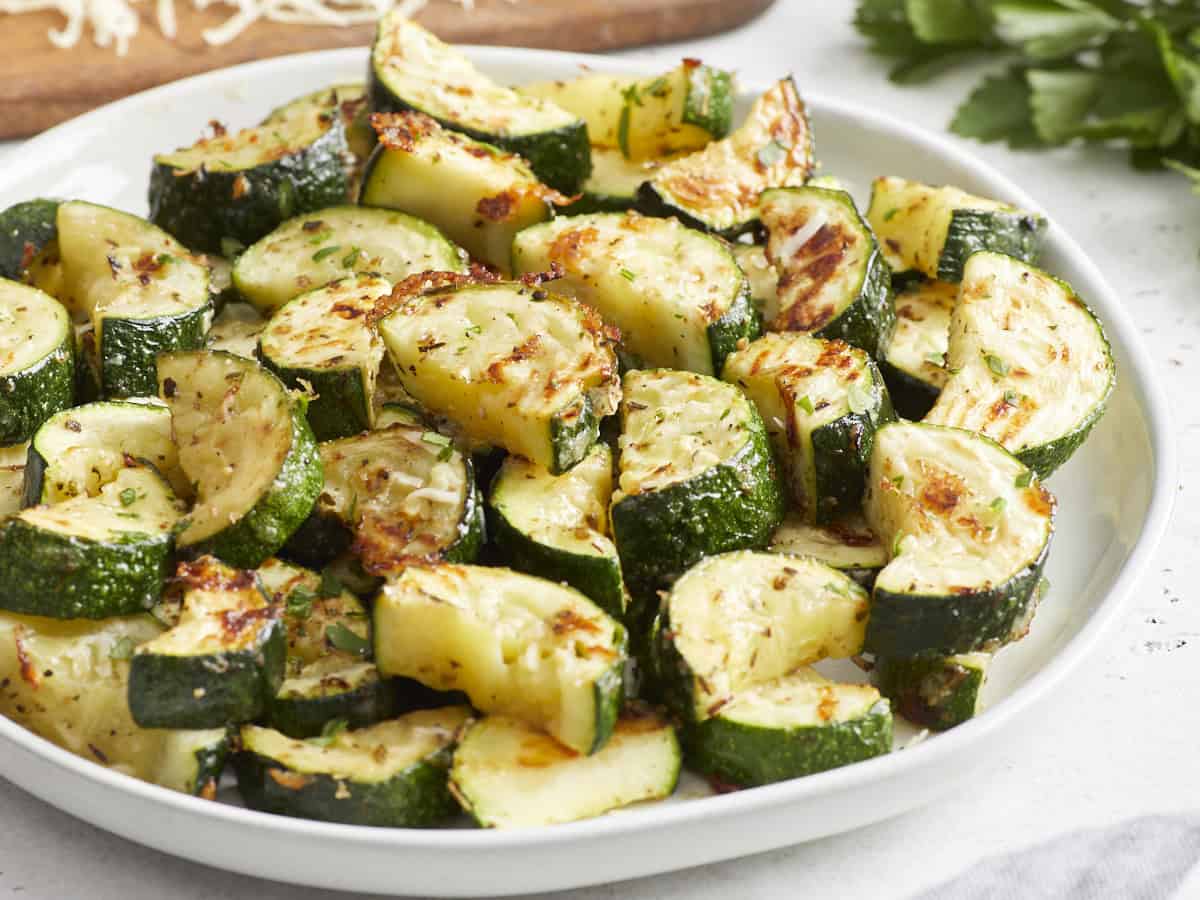 three-quarters view of roasted zucchini on a white plate.