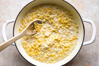 stirring creamed corn in a dutch oven with a wooden spoon.