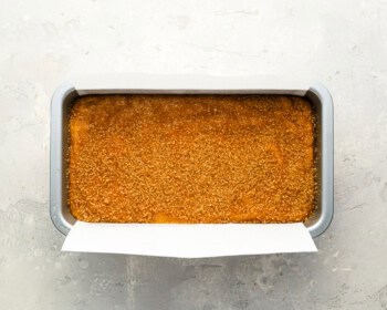 pumpkin bread batter in a greased loaf pan topped with turbinado sugar.