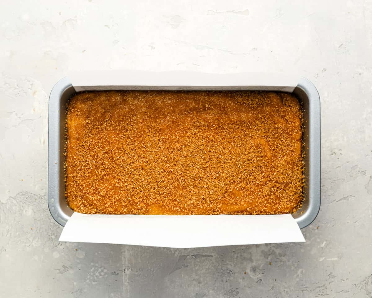 pumpkin bread batter in a greased loaf pan topped with turbinado sugar.