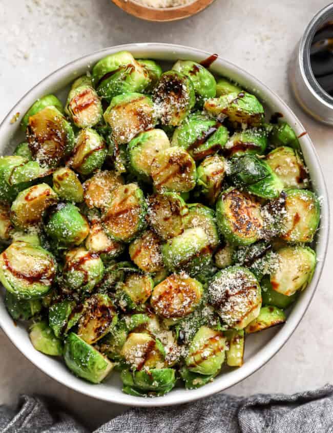 overhead view of garlic parmesan brussels sprouts in a bowl with balsamic drizzle.