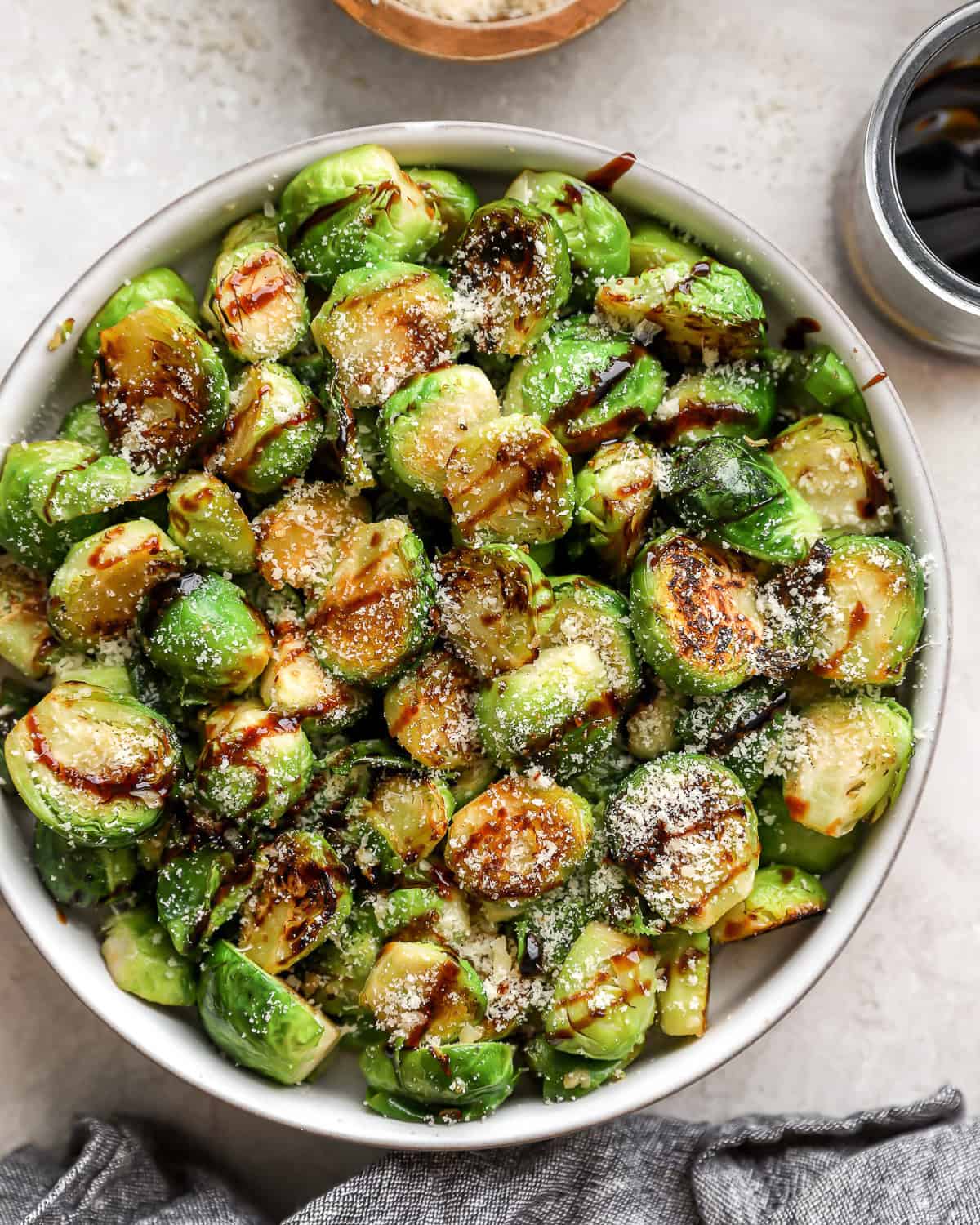 overhead view of garlic parmesan brussels sprouts in a bowl with balsamic drizzle.