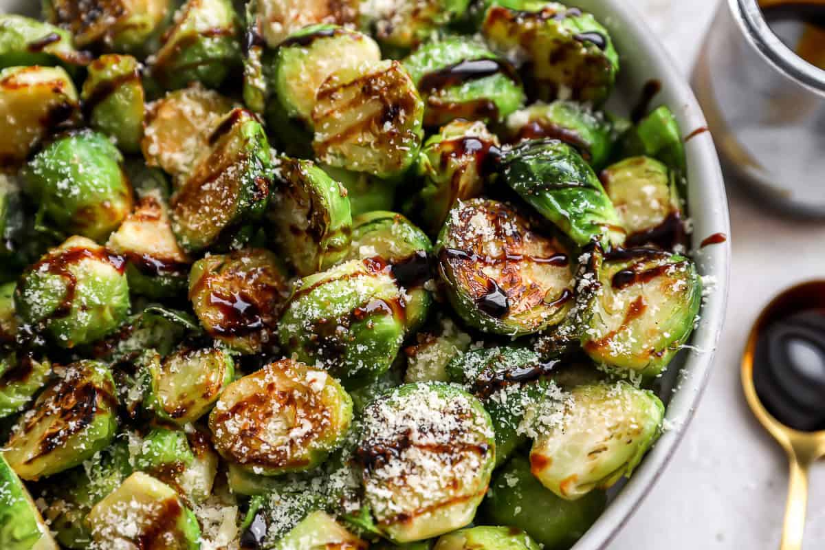 closeup view of garlic parmesan brussels sprouts in a bowl with balsamic drizzle.